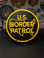 Round U.S. Border Patrol 3D printed plaque in black and yellow, displayed on a stand